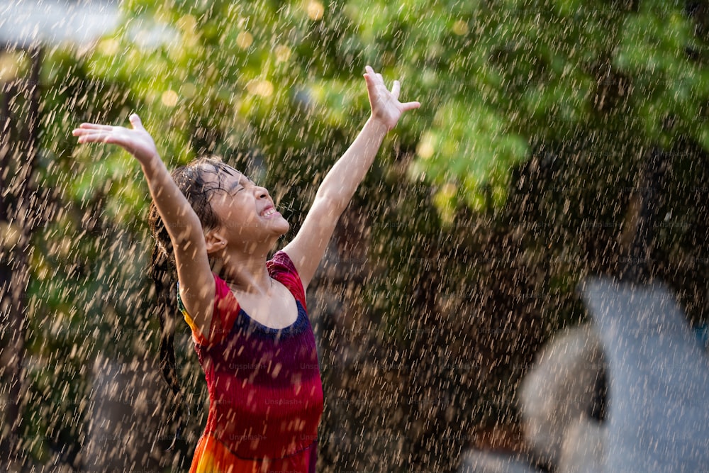 As crianças asiáticas brincando na chuva são felizes.