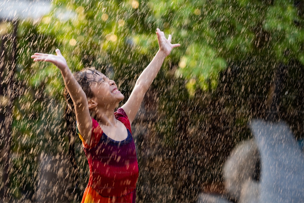 Les enfants asiatiques qui jouent sous la pluie sont heureux.