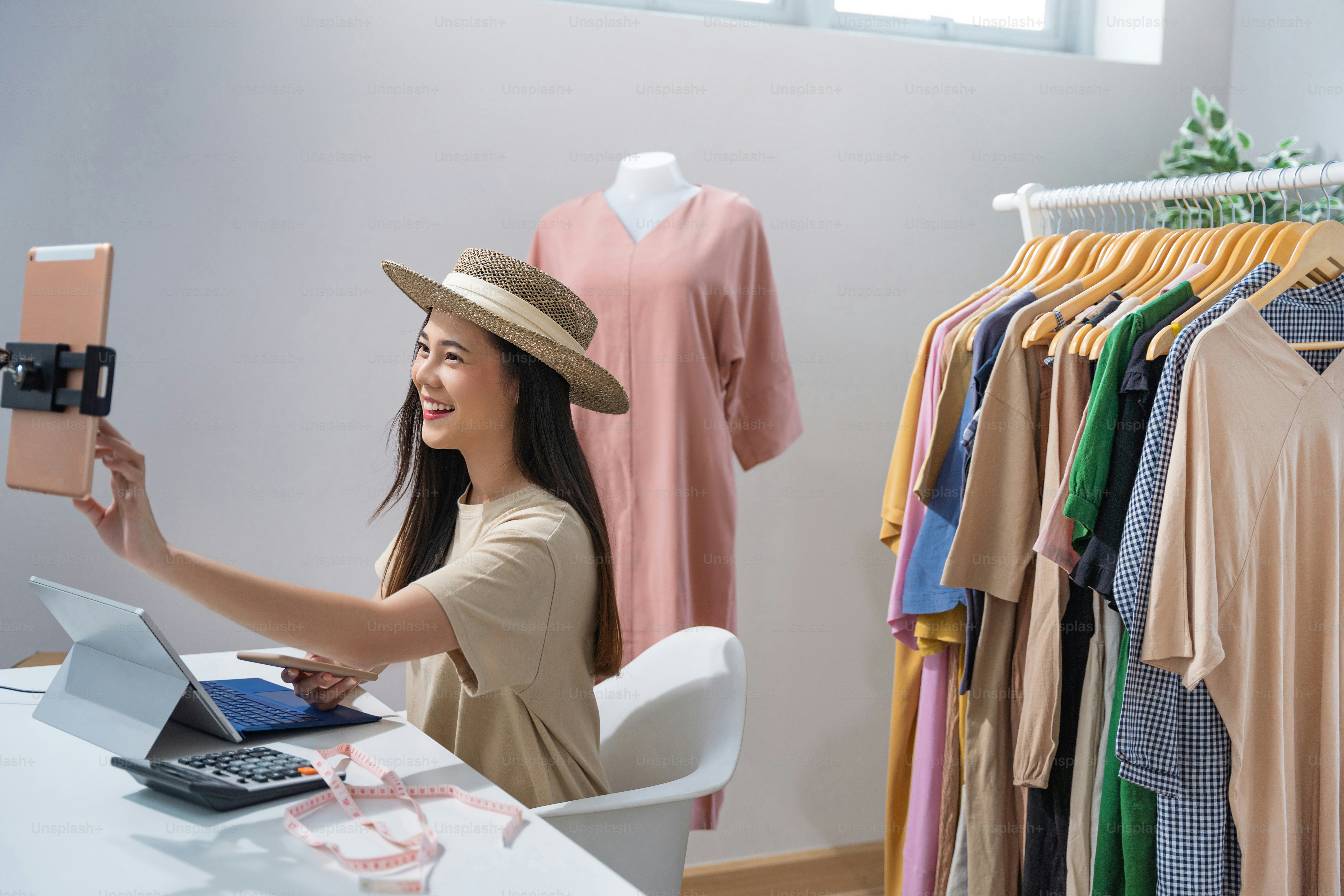 Asian woman selling vintage clothes, she is live on social media."rShe is answering customers questions.