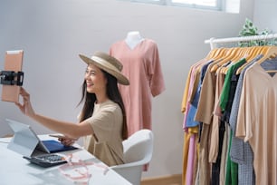 Asian woman selling vintage clothes, she is live on social media."rShe is answering customers questions.