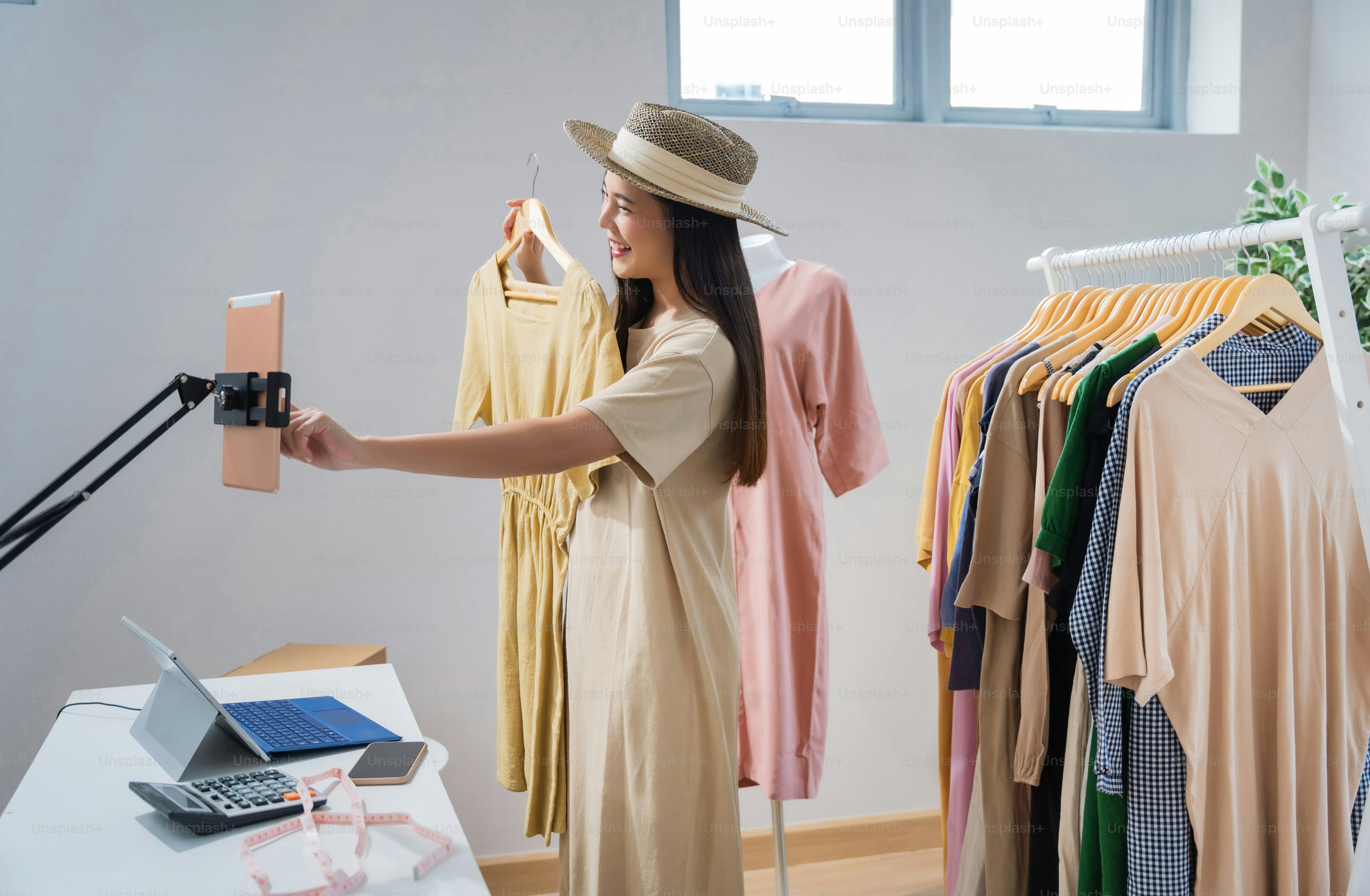 Asian woman selling vintage clothes, she is live on social media."rShe is answering customers questions.