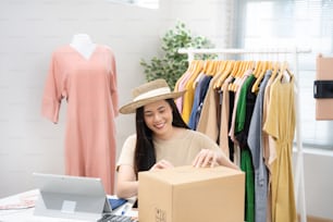 Mujer asiática que vende ropa vintage, está en vivo en las redes sociales. Ella empaca una caja