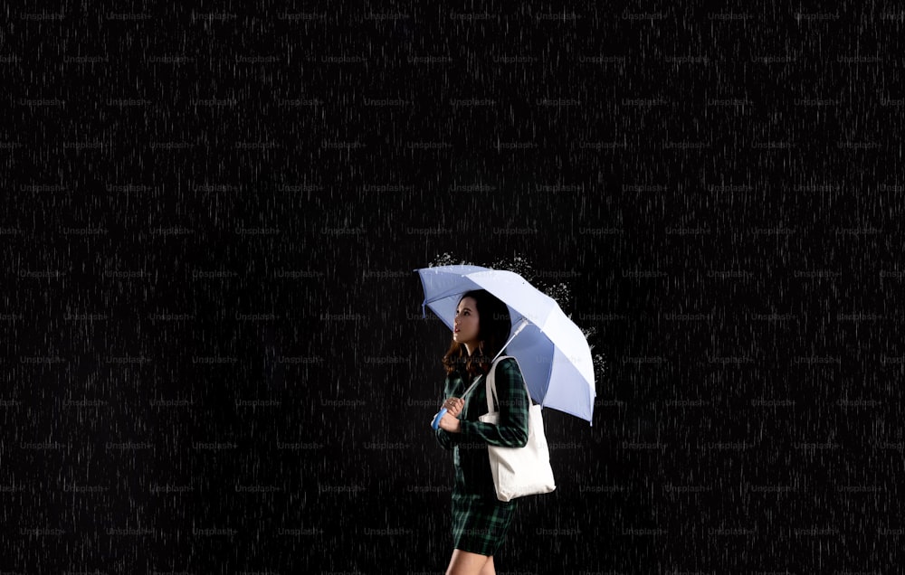 Mujer asiática, está en el paraguas de la lluvia.