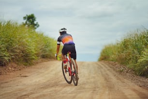 Asian man cycling on gravel road.