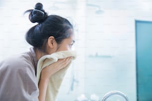 아시아 여성들은 얼굴을 씻은 후 깨끗한 얼굴을 닦았습니다 그녀는 화장실에있다