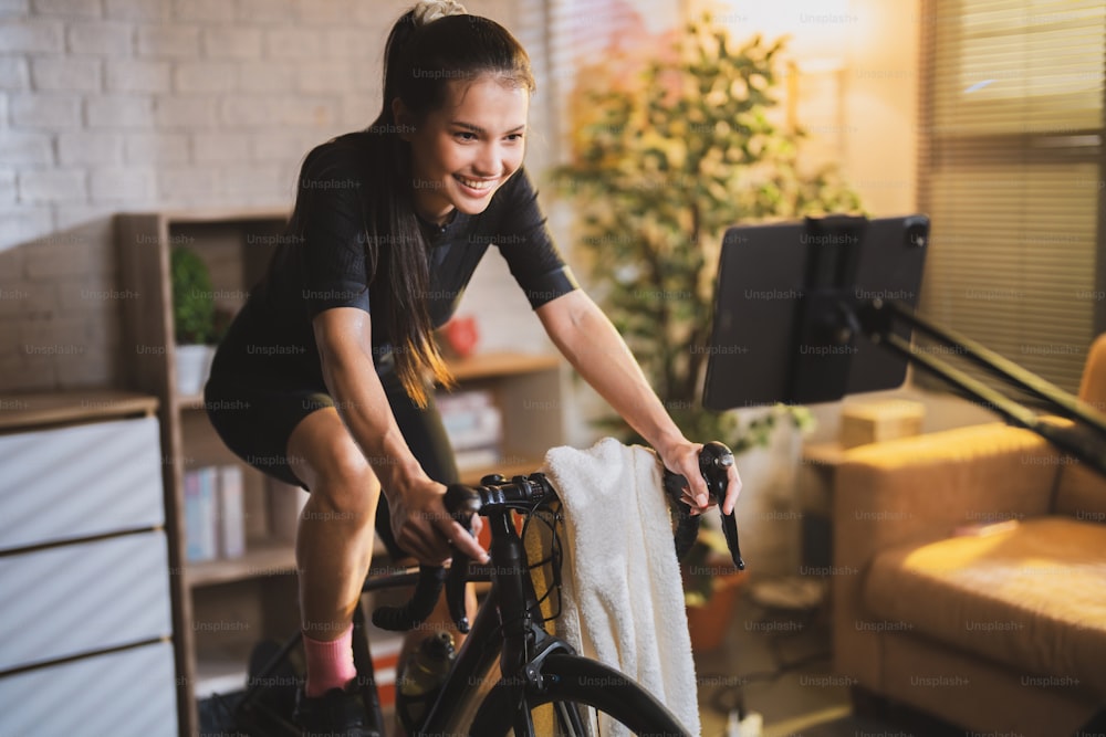 Asian woman cyclist. She is exercising in the house.By cycling on the trainer and play online bike games