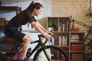 Asian woman cyclist. She is exercising in the house.By cycling on the trainer and play online bike games