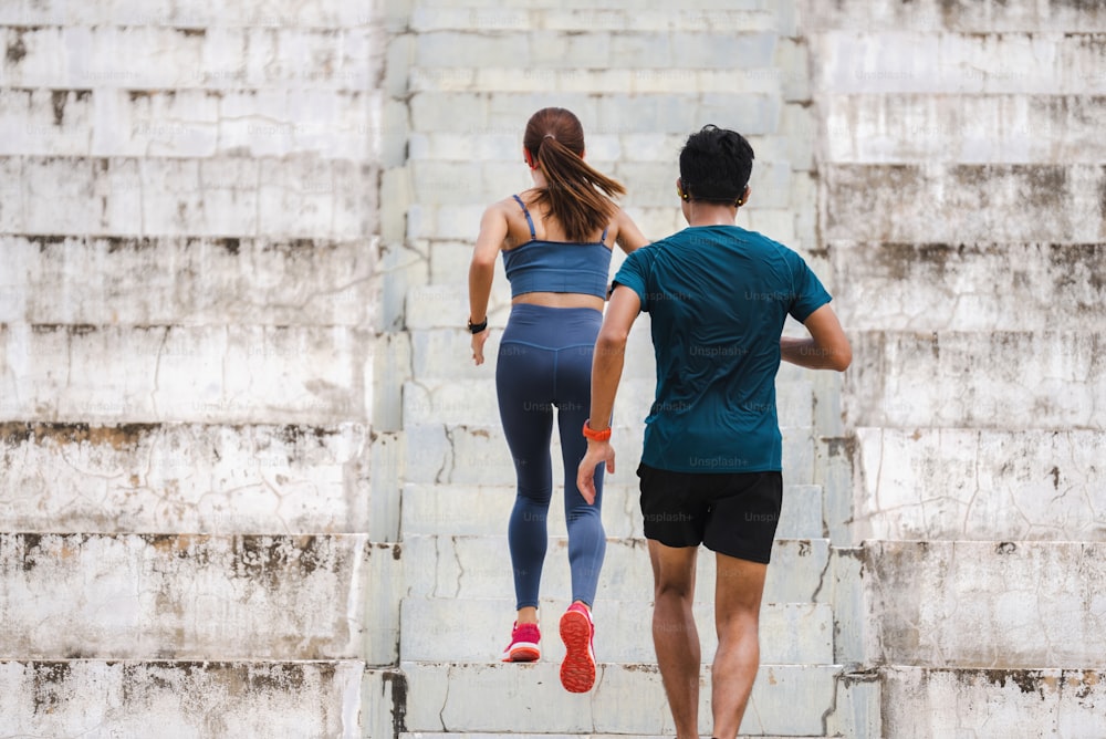 Um casal de asiáticos está se exercitando e correndo pelas escadas.