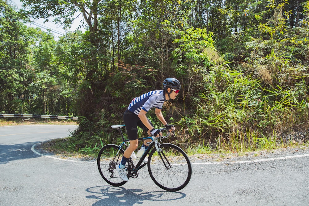 Asian men are cycling road bike in the morning.He is on a forest road.