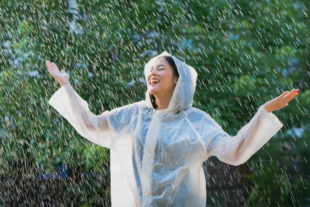 屋外でレインコートを着た雨の日のアジア人女性。彼女は幸せです。