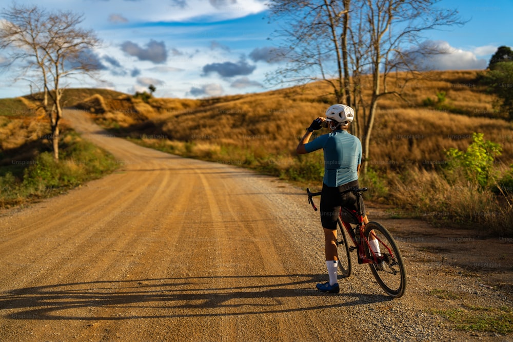 Cyclists practicing on gravel roads. he is drinking water