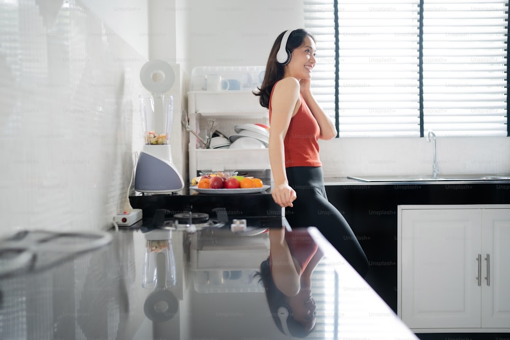 Asian woman making fruit smoothie after exercise. she is listening to music