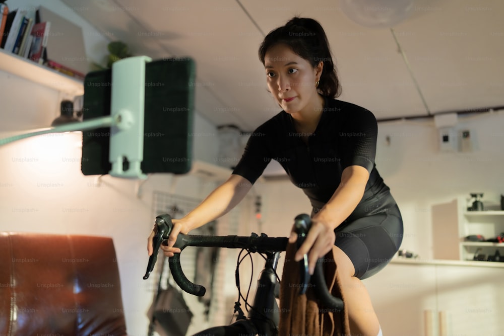 Female Asian cyclist, She is exercising at home. She rides a bike simulator.