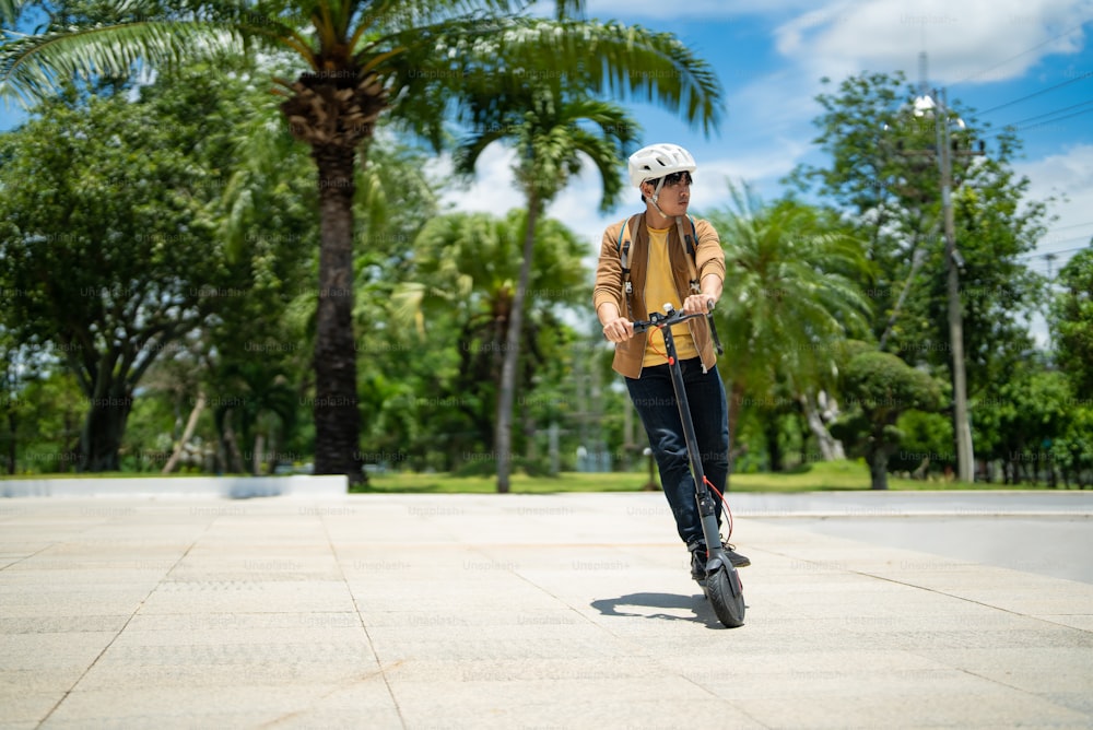 An Asian man rides an electric scooter to work.