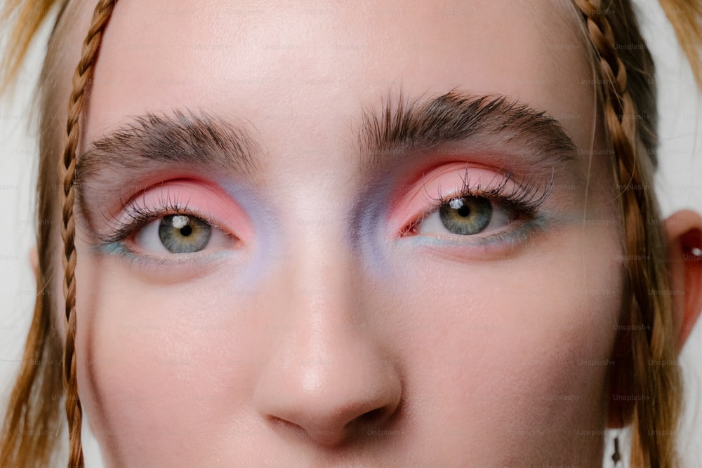 a close up of a woman's face with pink and blue makeup