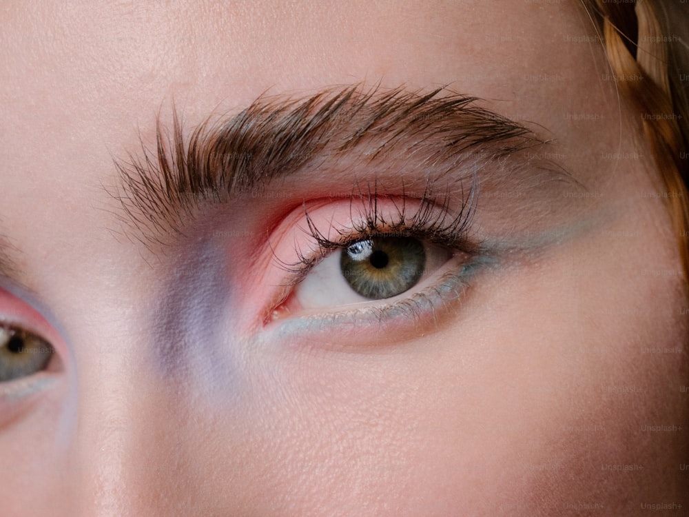 a close up of a woman's eye with pink and blue makeup