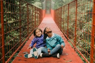 a man and a woman sitting on a red bridge