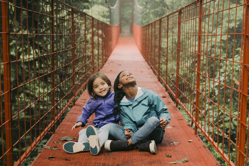 a man and a woman sitting on a red bridge