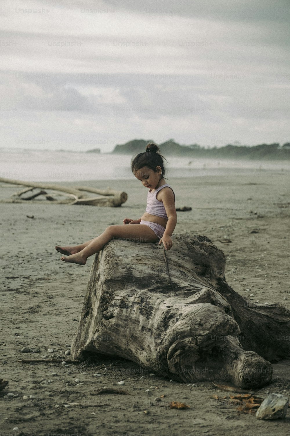 a girl sitting on a rock on a beach