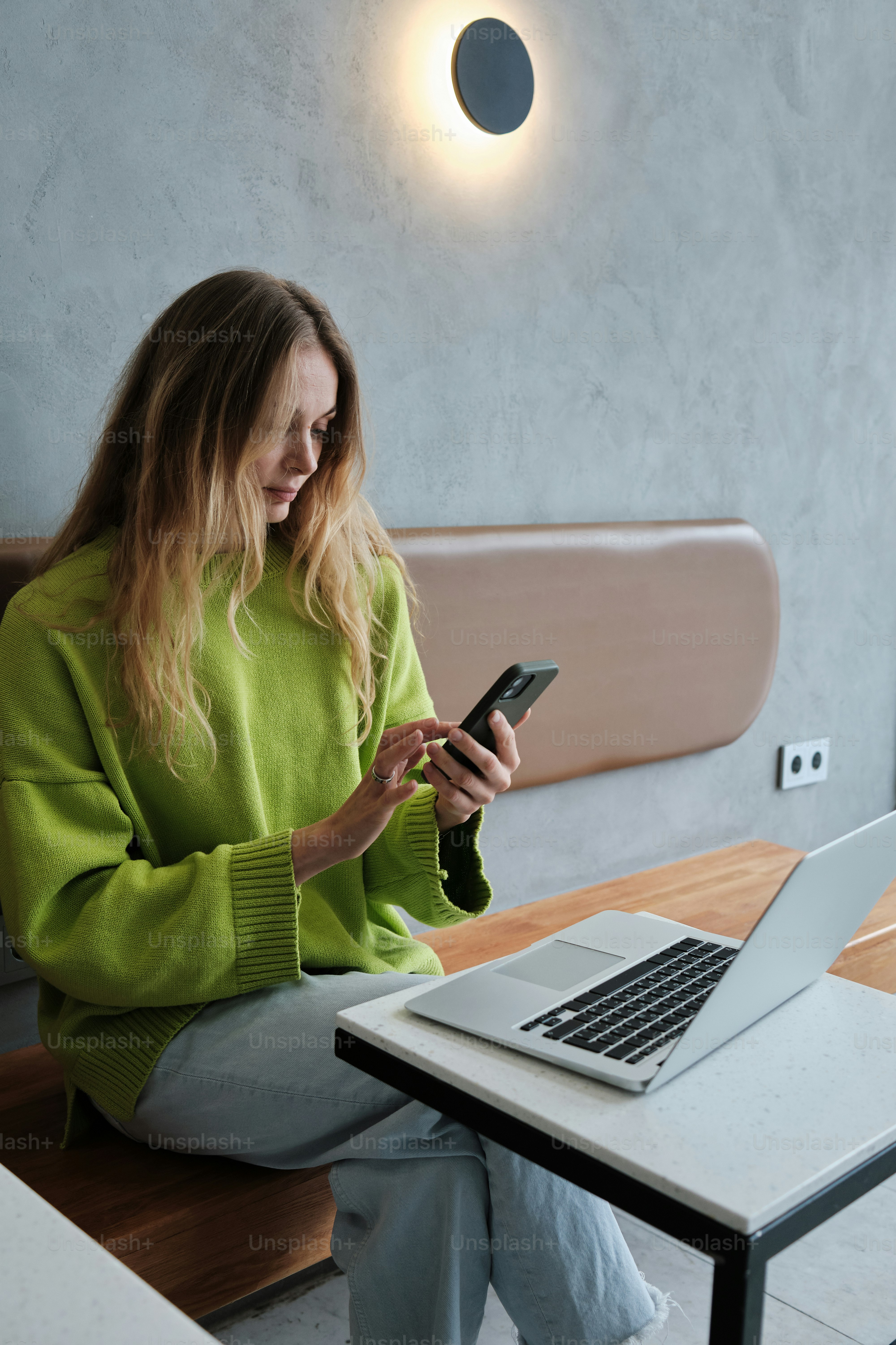 Une femme assise à une table regardant son téléphone