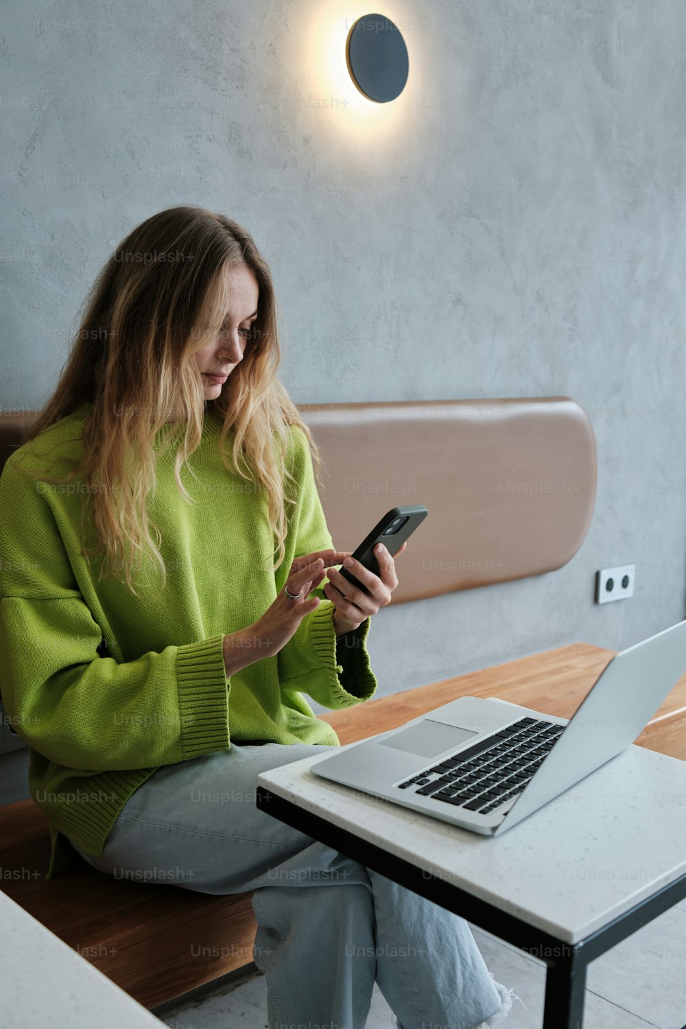 a woman sitting at a table looking at her phone