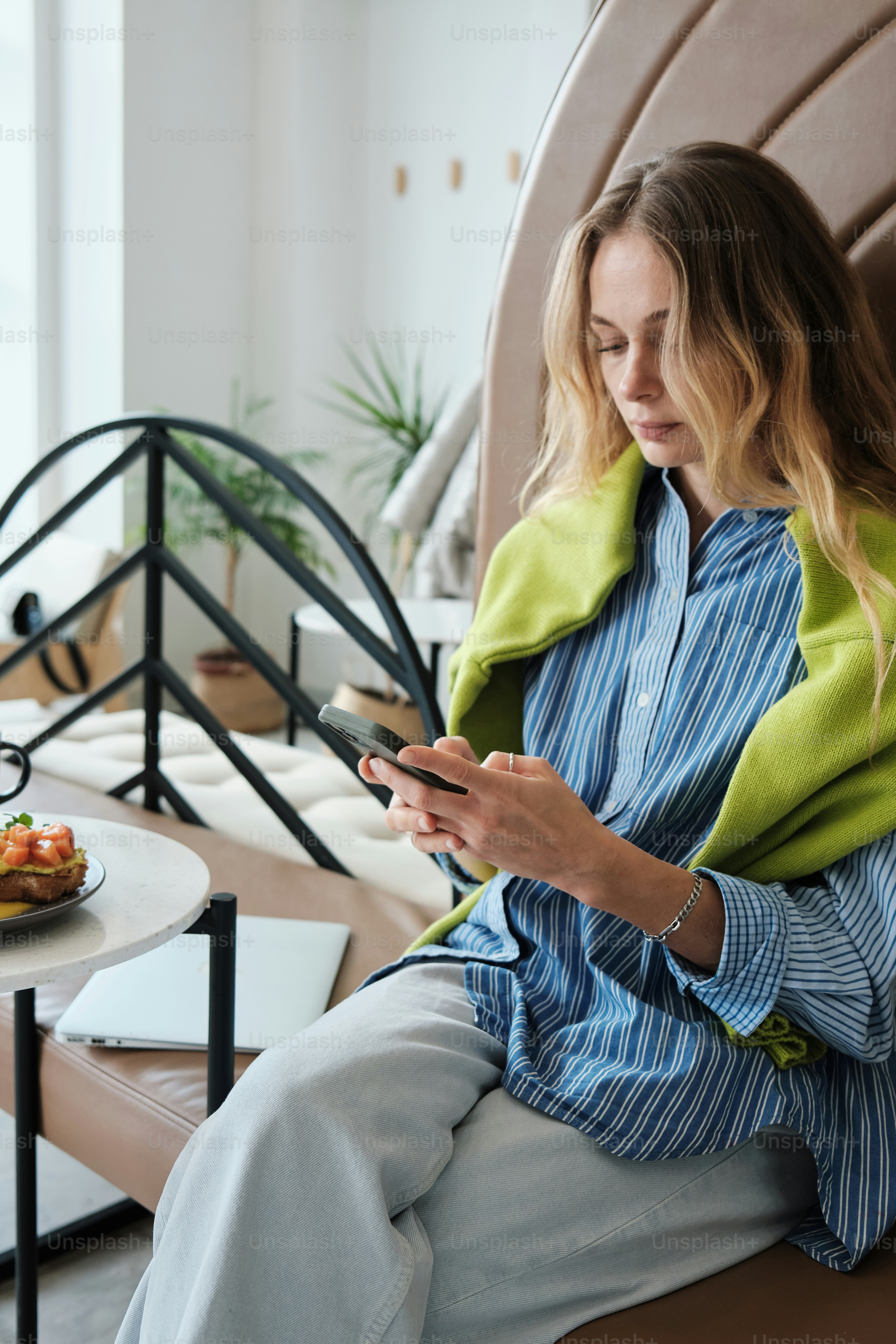 Une femme assise sur une chaise regardant son téléphone