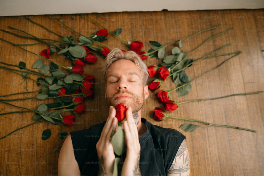 a person with a beard and a mustache with a rose bush behind him