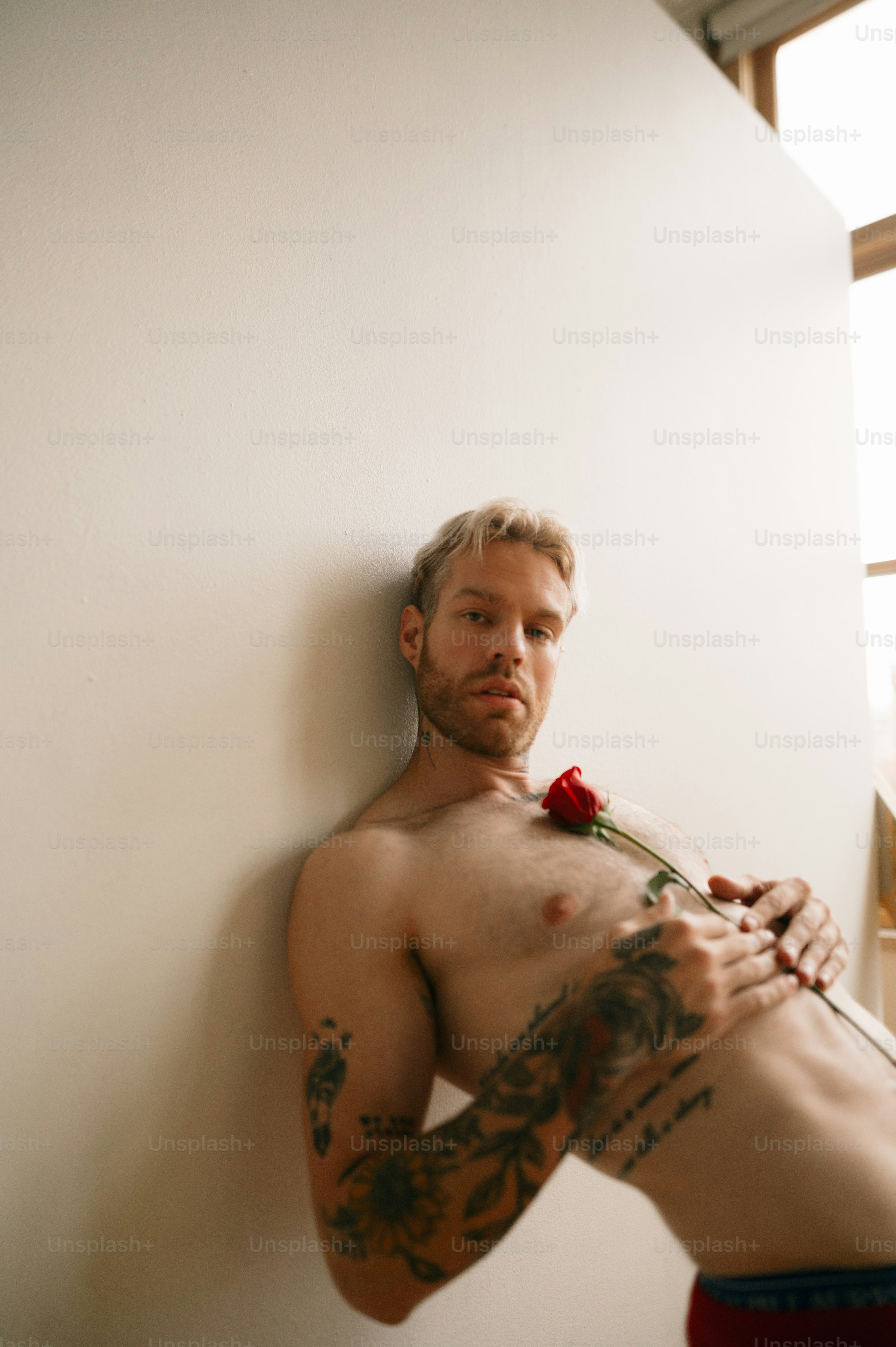 Eine Person mit Tätowierungen, die eine Rose hält