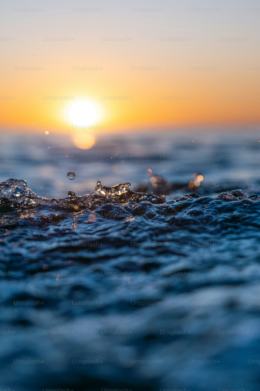 a group of water droplets on a surface with the sun in the background