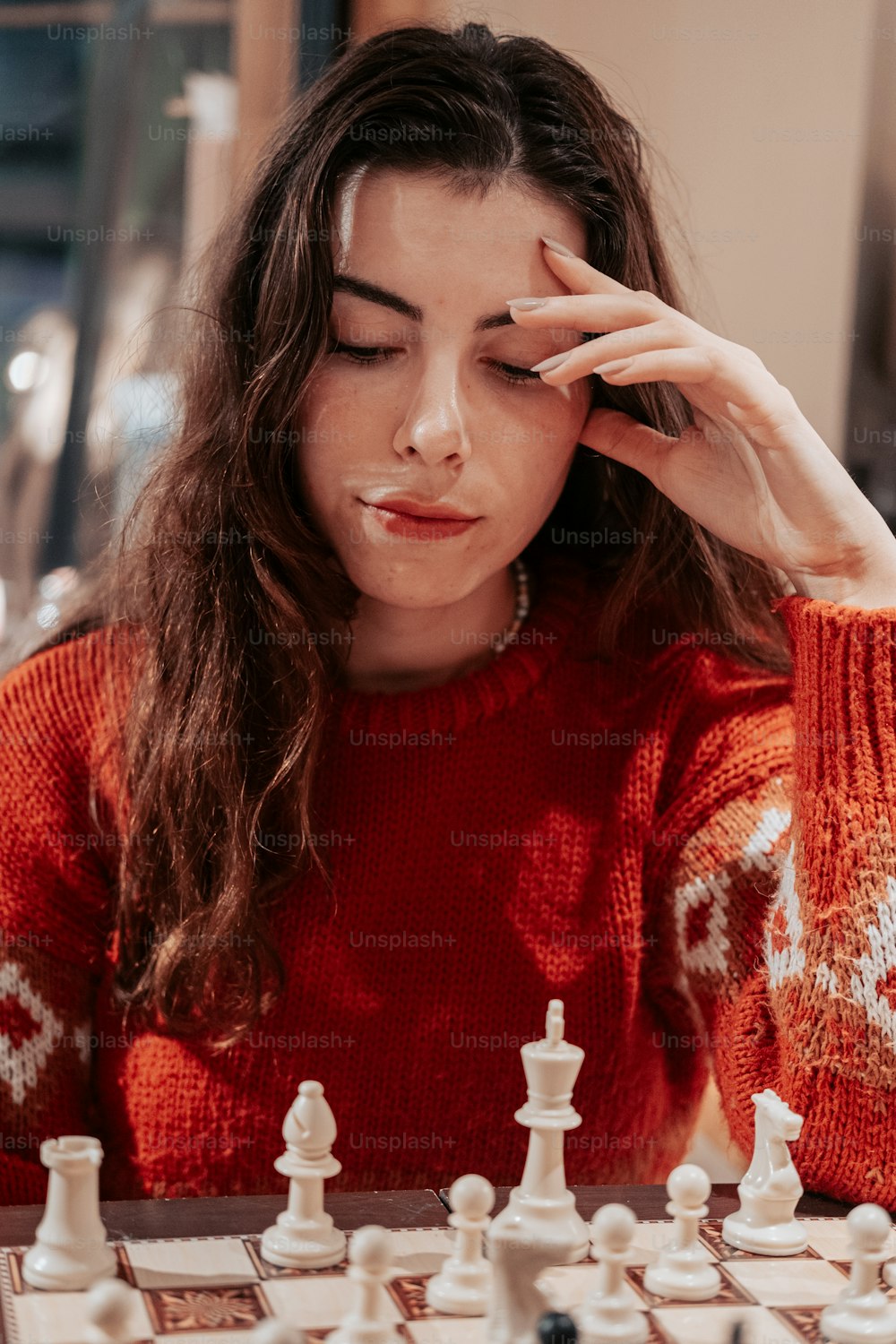 a woman with her hand on her face and a chess board