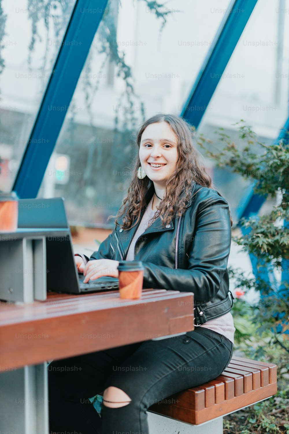 a woman sitting at a table with a laptop and a glass of beer