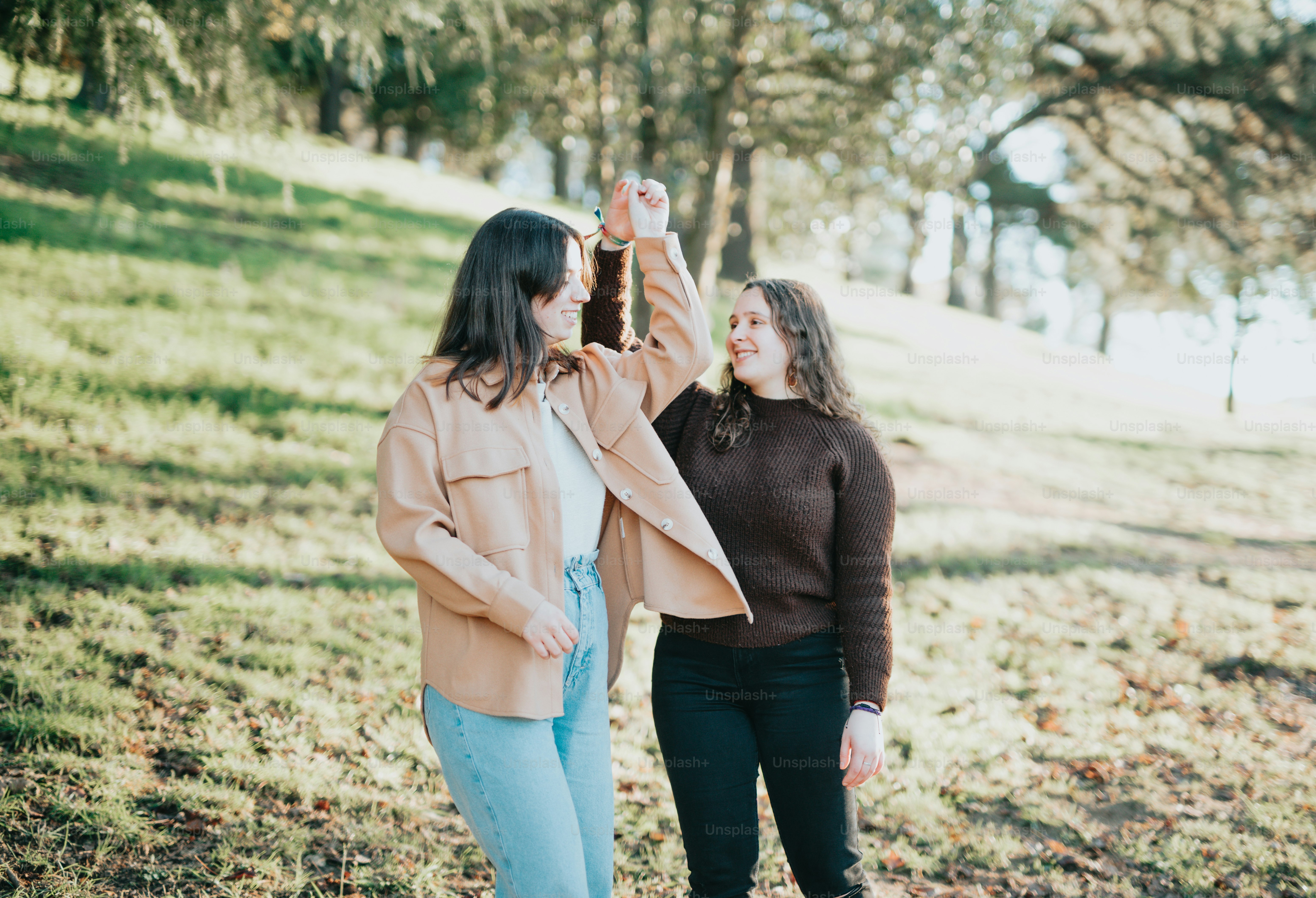 A couple of women walking on a path with trees and grass photo ...