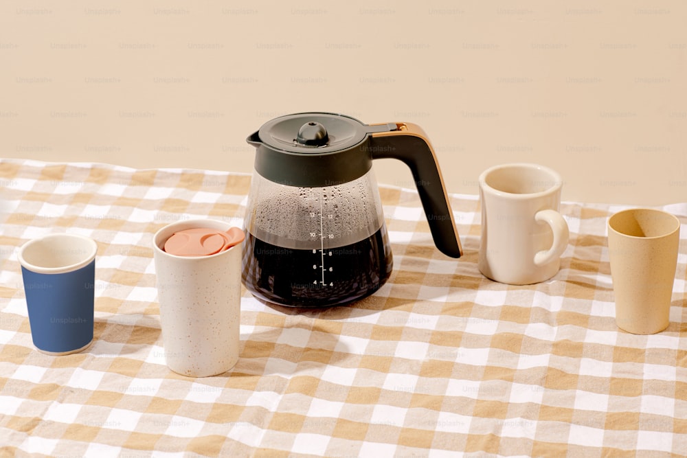 a tea kettle and cups on a table