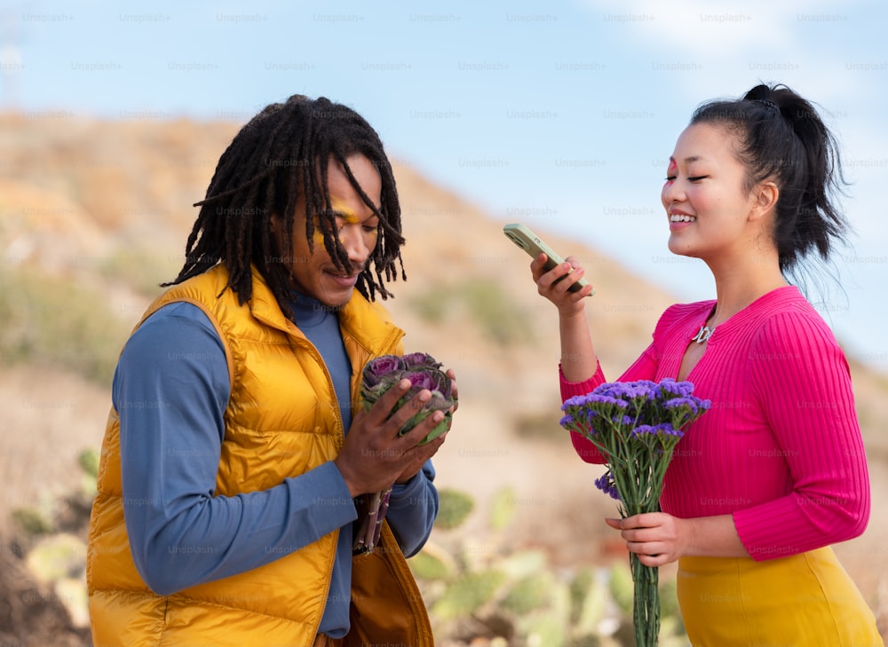 una persona che tiene fiori e un telefono cellulare accanto a una persona che tiene fiori