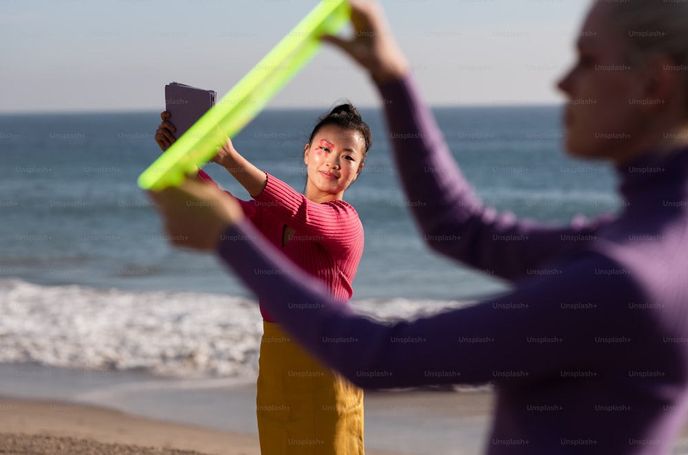 a woman holding a neon green frisbee next to another woman