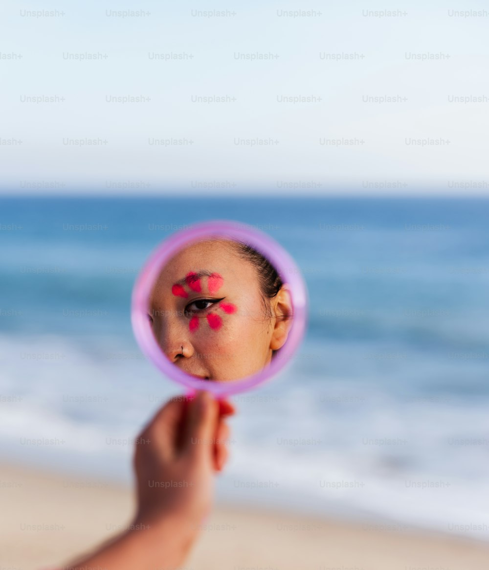 a hand holding a pink object with a cartoon face on it