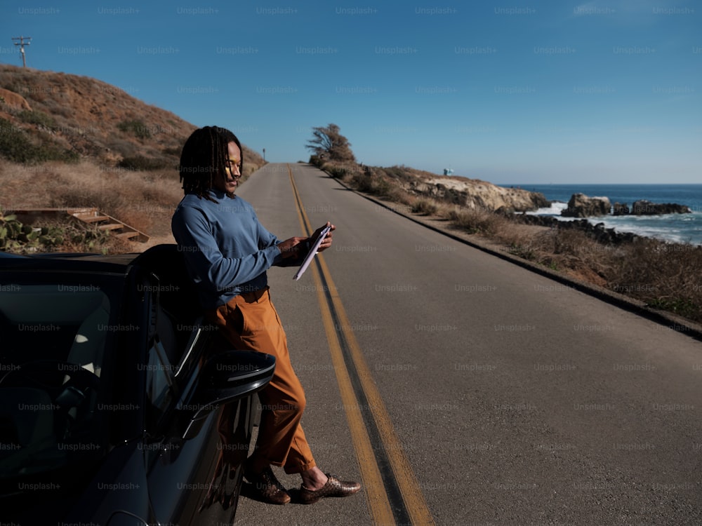 a man sitting on the side of a road looking at a tablet