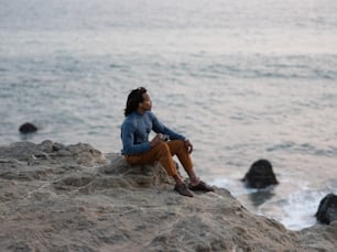 Un hombre y una mujer sentados en una roca junto al agua