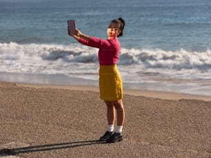 a boy holding a phone on a beach