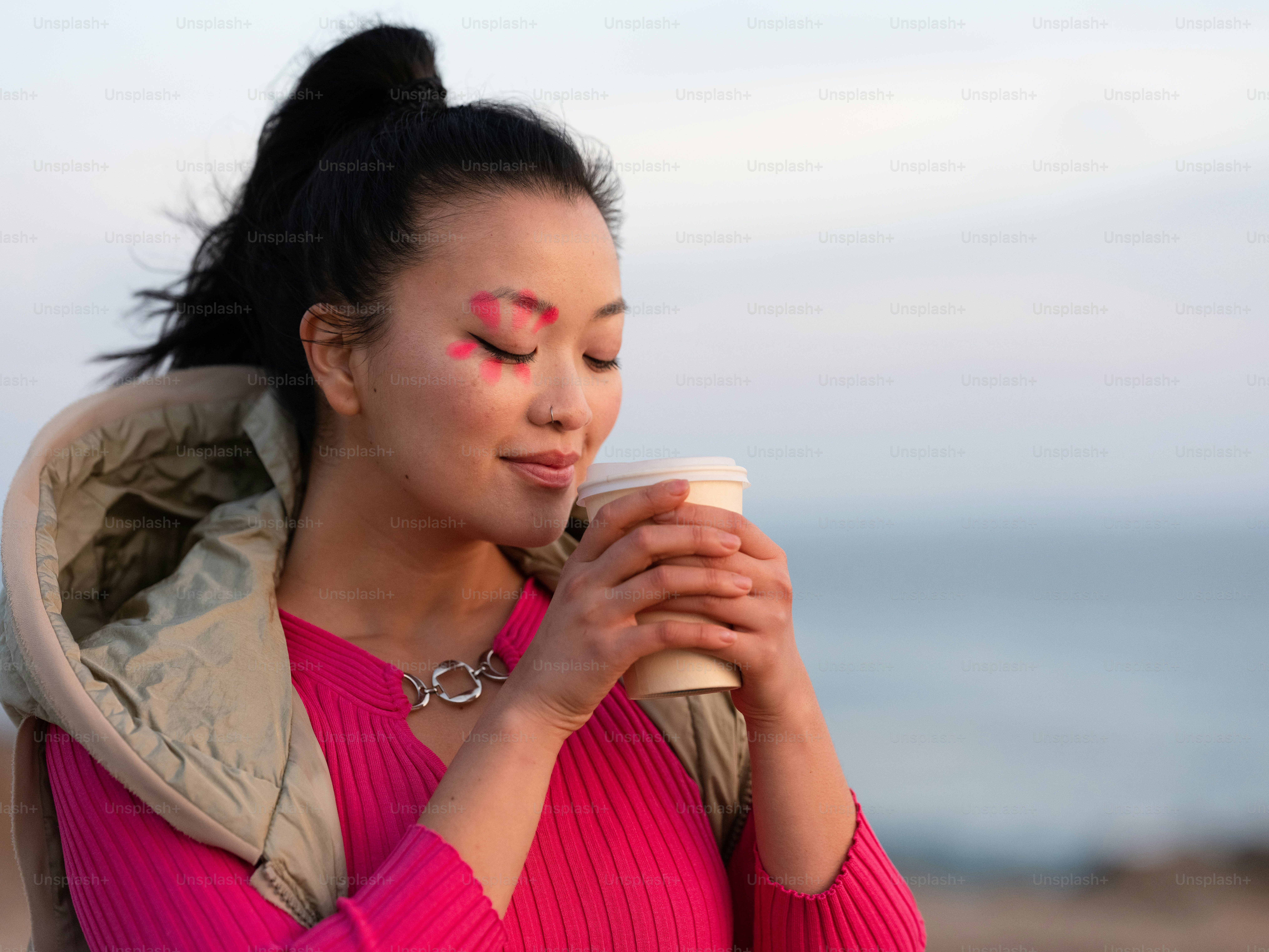 a person with red paint on the face holding a cup