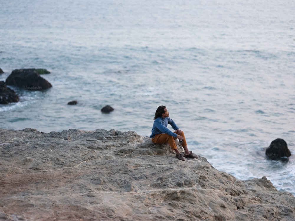 물가 바위에 앉아있는 남자