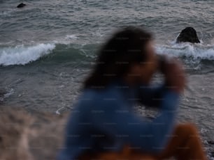 Eine Person, die auf einem Felsen sitzt und auf den Ozean schaut