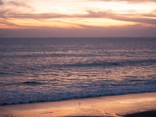 Una playa con olas y una puesta de sol