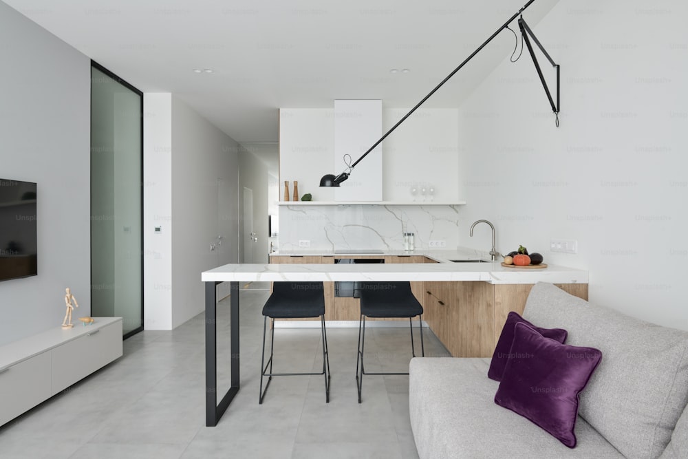 a kitchen with a white counter and black chairs