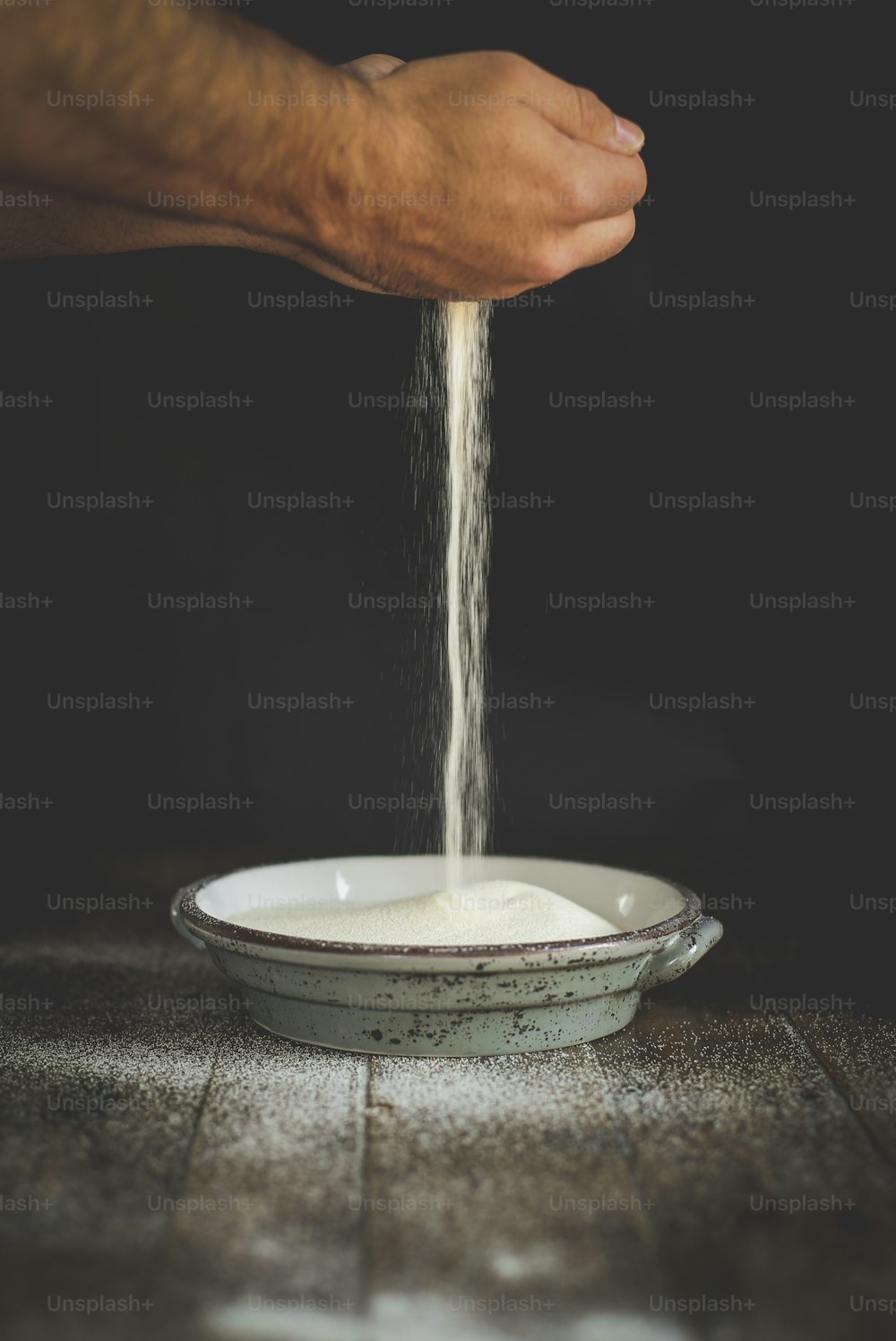 a hand pouring a liquid into a bowl