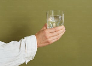 eine Hand, die ein Glas Wasser hält