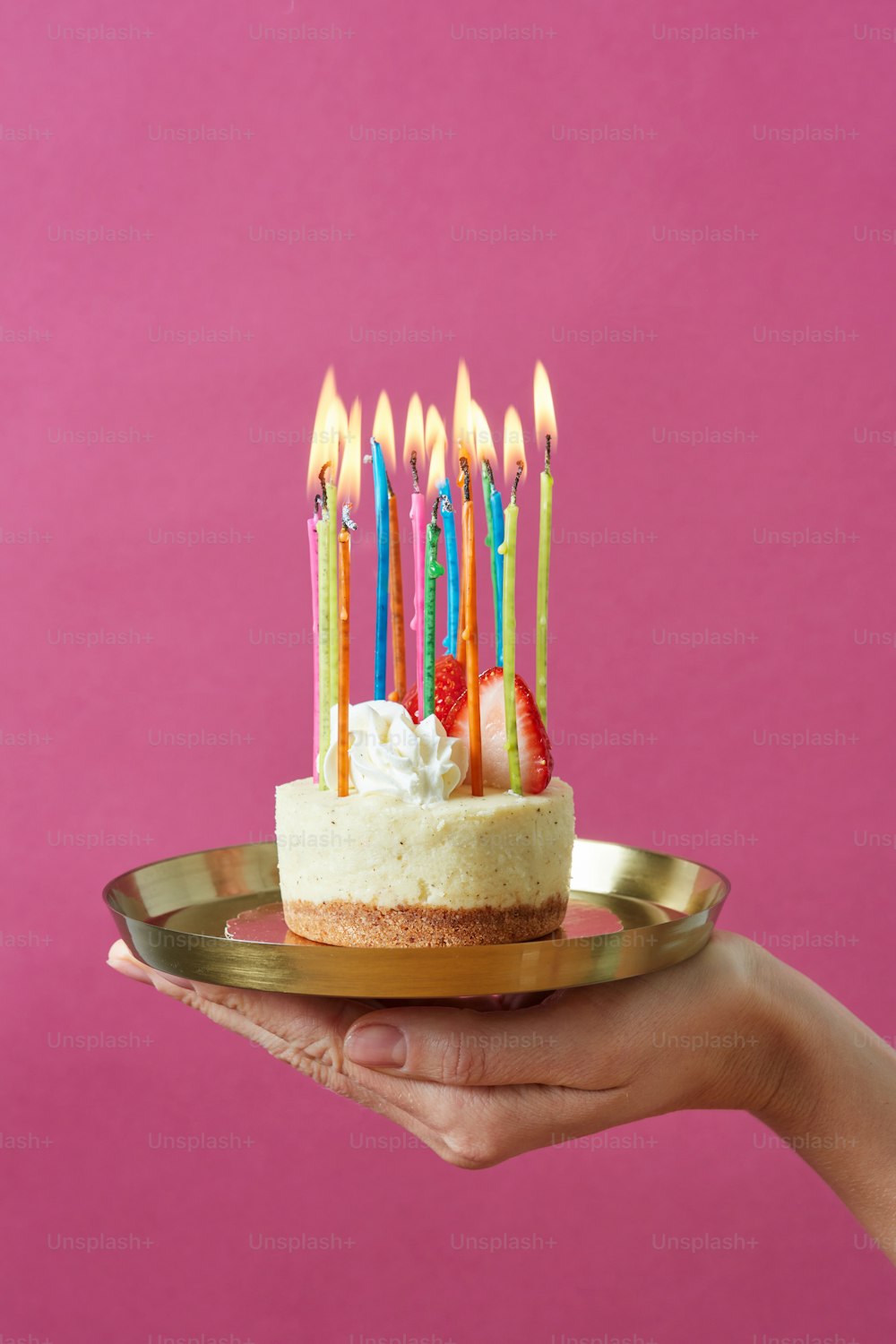 a hand holding a plate with a cake with candles on it