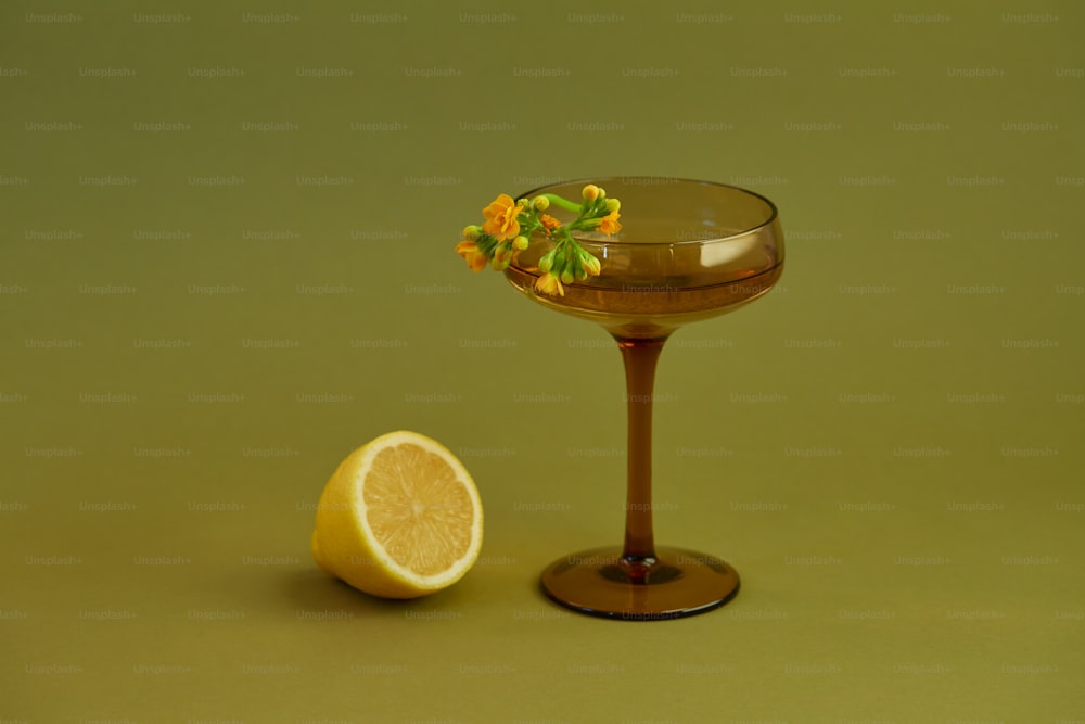 a glass with a lemon and a lemon slice on a green background
