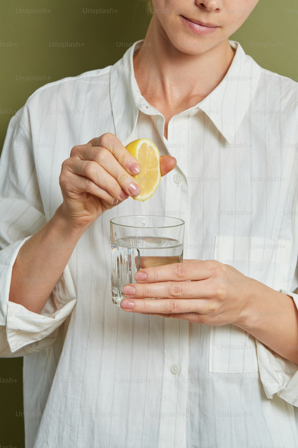 a person holding a lemon and a glass of water