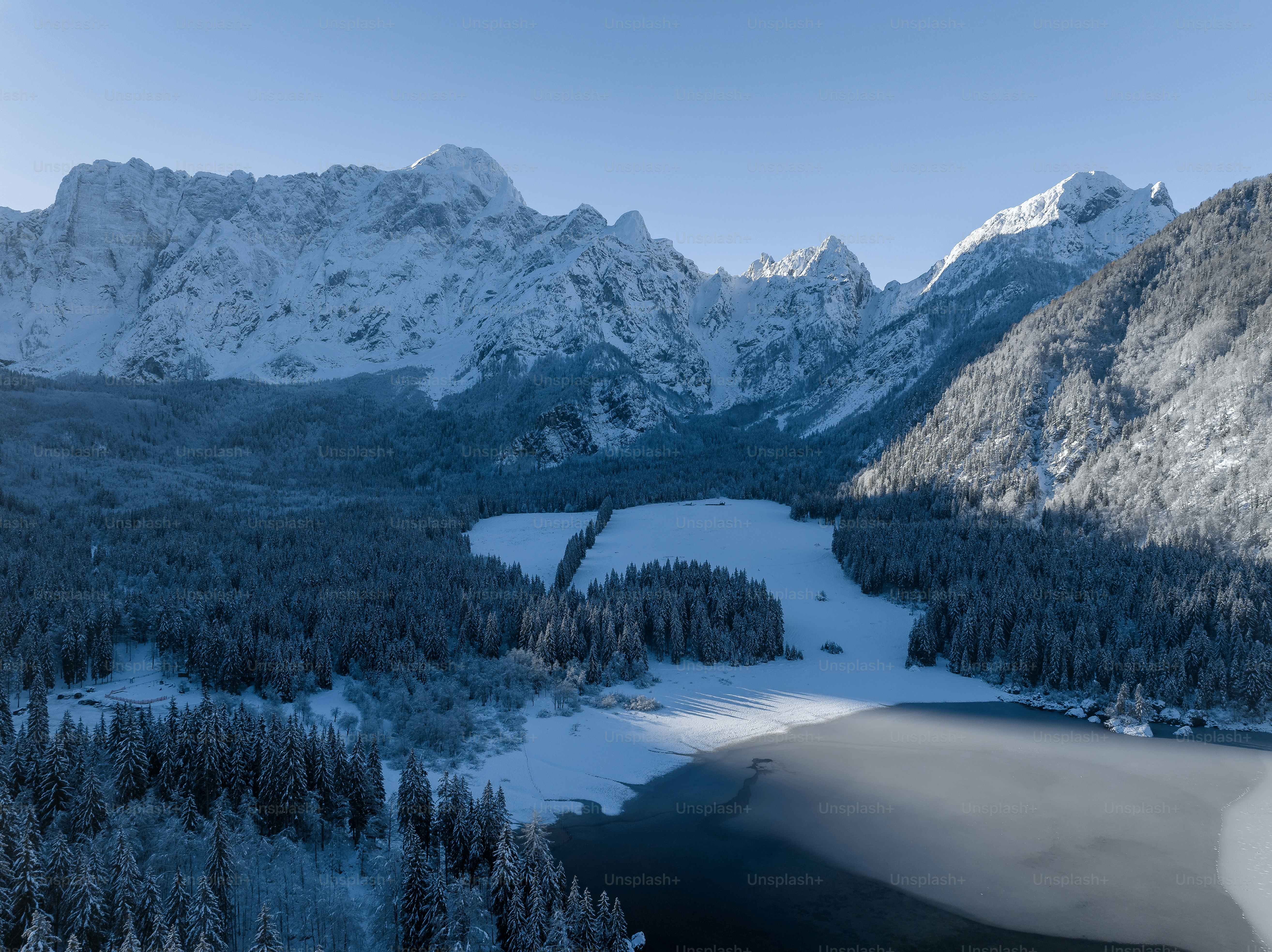 A lake surrounded by snow covered mountains and trees photo – Beautiful ...